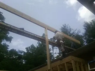 Carpenter setting a ridge beam over a new addition frame — Ice Dam Removal by Roofing Brothers in Mediapolis