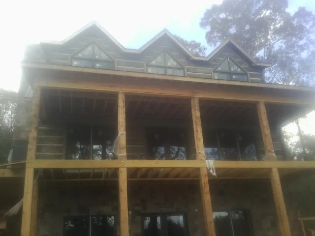 Dormers and porch framing on a large log home under construction — Roof Coating work by our crew in Mediapolis