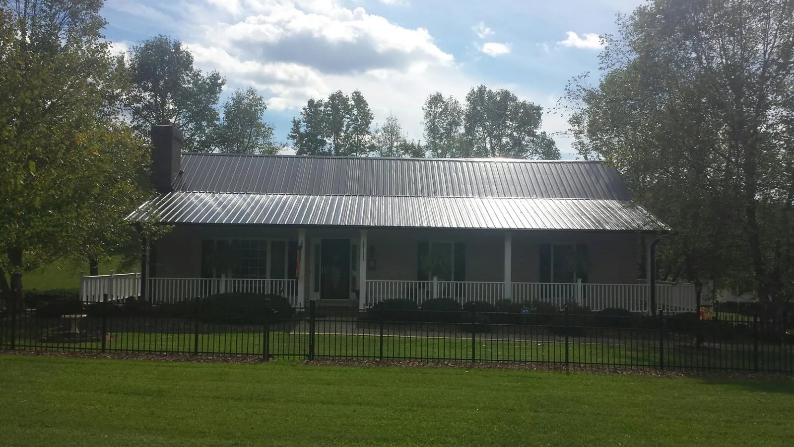 Gray metal roof on a brick ranch with a full width front porch — Gutter Guard Installation work by our crew in Mediapolis
