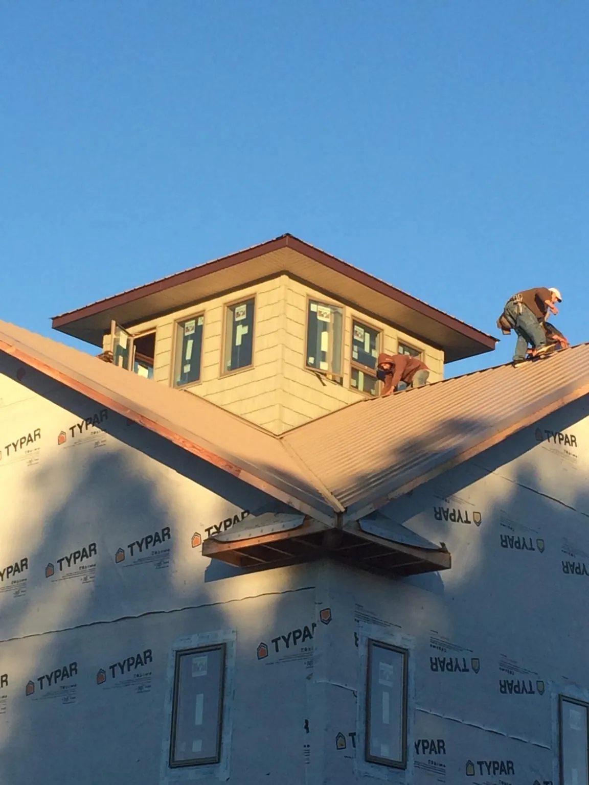 Roofers working around a rooftop cupola on a new metal roof at sunset — Roof Waterproofing in Mediapolis by Roofing Brothers